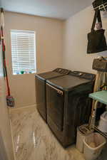 Laundry room featuring washer and dryer and marble finish flooring
