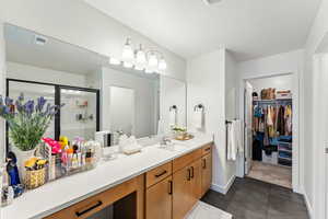 Bathroom featuring vanity, a stall shower, baseboards, a walk in closet, and tile patterned flooring