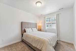 Carpeted bedroom featuring baseboards and a textured ceiling