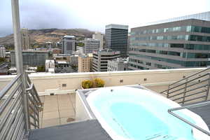 Balcony featuring view of pool, a mountain view, a jacuzzi, and a view of city