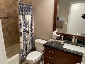 Full bath with toilet, vanity, and shower / tub combo with curtain