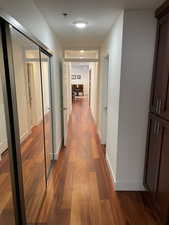Hallway with dark wood-style flooring and baseboards
