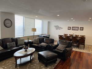 Living room with dark wood finished floors, recessed lighting, a textured ceiling, and baseboards