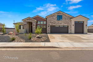 Contemporary home with stone siding, driveway, a garage, and stucco siding