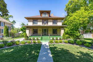 American foursquare style home with brick siding, covered porch, and a chimney