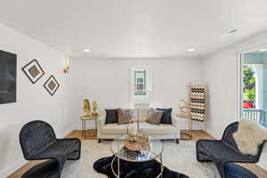 Living area with plenty of natural light, baseboards, wood finished floors, and recessed lighting
