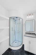 Full bath with a shower stall, tile patterned flooring, vanity, and baseboards