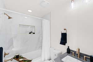 Bathroom featuring toilet, shower / tub combo with curtain, and vanity