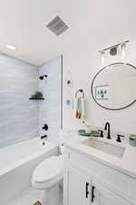 Bathroom featuring vanity, marble look tiles, bathing tub / shower combination, and toilet