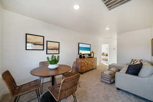 Dining room with light colored carpet and recessed lighting