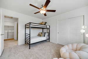 Bedroom featuring separate washer and dryer, carpet, and baseboards