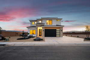 View of front of house featuring stone siding, a garage, stucco siding, and driveway