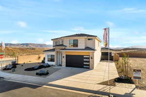 Modern home featuring a garage, a mountain view, driveway, and stucco siding