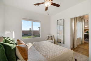 Bedroom with a chandelier, a ceiling fan, baseboards, and wood finished floors