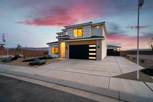 Contemporary house featuring a garage, stone siding, driveway, and stucco siding