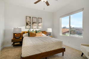 Bedroom featuring light colored carpet, baseboards, and ceiling fan