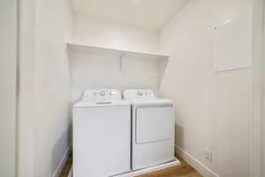 Laundry area featuring washing machine and dryer, baseboards, and wood finished floors