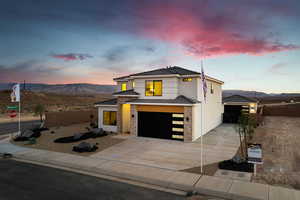 View of front facade with a garage, driveway, a mountain view, and stucco siding
