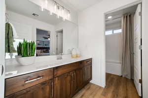 Bathroom featuring wood finished floors, vanity, ensuite bathroom, ceiling fan, and shower / bath combo