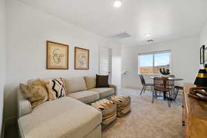 Living room with light colored carpet, recessed lighting, and baseboards