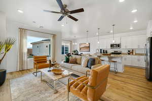 Living room with a ceiling fan, light wood finished floors, recessed lighting, and baseboards