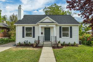 Bungalow-style house with a front lawn, a chimney, roof with shingles, and central air condition unit