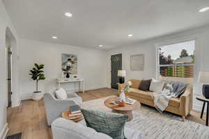 Living area with arched walkways, light wood-style floors, recessed lighting, and baseboards
