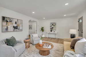 Living room with arched walkways, wood finished floors, recessed lighting, and baseboards