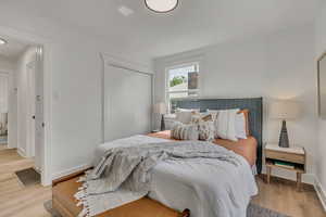 Bedroom with light wood-style floors, a closet, and baseboards