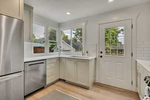 Kitchen with stainless steel appliances, a sink, light wood-style flooring, light countertops, and recessed lighting