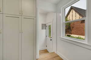 Entryway featuring light wood-type flooring, electric panel, and baseboards