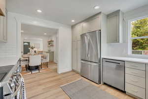 Kitchen featuring appliances with stainless steel finishes, gray cabinetry, arched walkways, light countertops, and recessed lighting