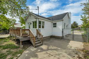 Rear view of property with a deck, roof with shingles, a gate, and a chimney