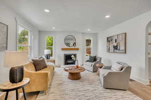 Living room with arched walkways, recessed lighting, wood finished floors, a fireplace, and baseboards