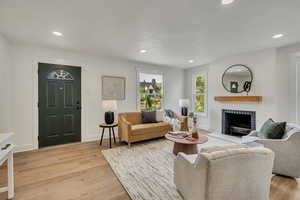 Living area featuring a brick fireplace, recessed lighting, light wood-style flooring, and baseboards