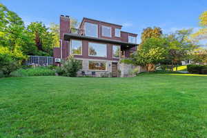 Back of property with a yard and brick siding