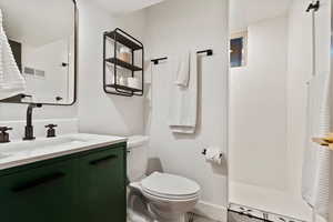 Bathroom featuring vanity, toilet, a walk in shower, baseboards, and tile patterned floors