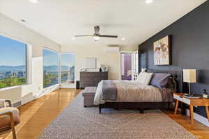 Bedroom featuring a wall unit AC, a mountain view, recessed lighting, light wood-style floors, and a ceiling fan