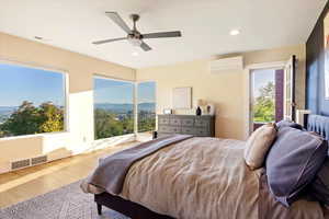 Bedroom featuring a wall unit AC, wood finished floors, access to outside, ceiling fan, and recessed lighting
