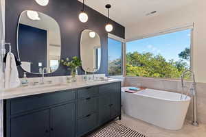 Full bath featuring tile walls, double vanity, a freestanding tub, and tile patterned floors