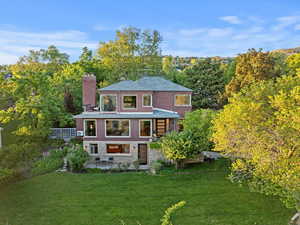 Back of house with a chimney, a yard, a patio, and brick siding