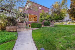 View of home's exterior with a lawn, stairway, and brick siding