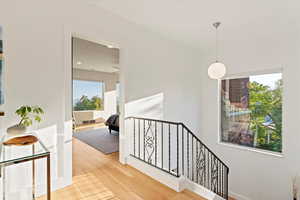 Hallway with an upstairs landing, light wood finished floors, and recessed lighting