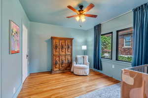 Bedroom featuring light wood-style floors, baseboards, and ceiling fan