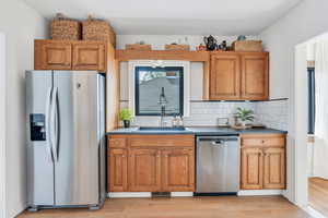 Kitchen featuring stainless steel appliances, a sink, light wood finished floors, and brown cabinetry