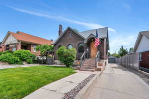Tudor home with brick siding, a front lawn, an outbuilding, a shingled roof, and a garage