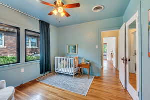 Bedroom with light wood-type flooring, baseboards, and a crib