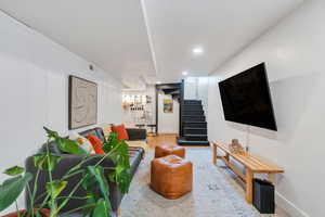 Living area with wood finished floors, stairs, baseboards, and recessed lighting