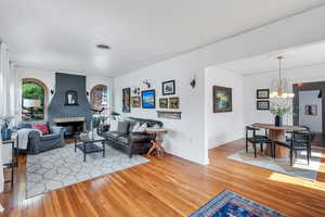 Living room featuring hardwood / wood-style flooring, a chandelier, baseboards, and a large fireplace