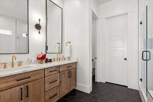 Full bath with double vanity, a stall shower, toilet, tile patterned floors, and baseboards